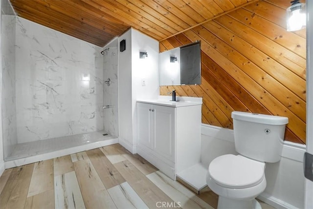 bathroom featuring lofted ceiling, vanity, tiled shower, wooden walls, and wooden ceiling