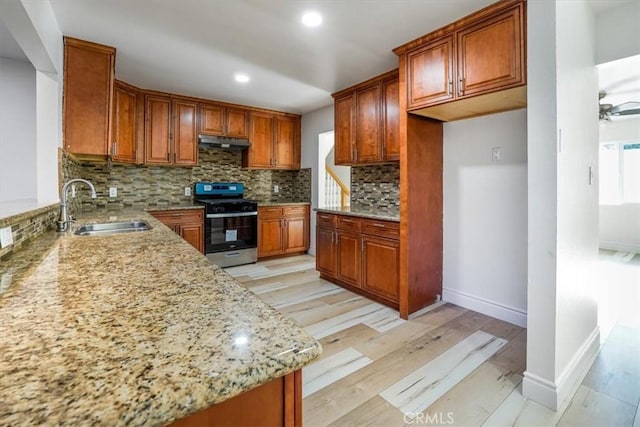 kitchen featuring ceiling fan, tasteful backsplash, sink, stainless steel range with gas cooktop, and light stone countertops