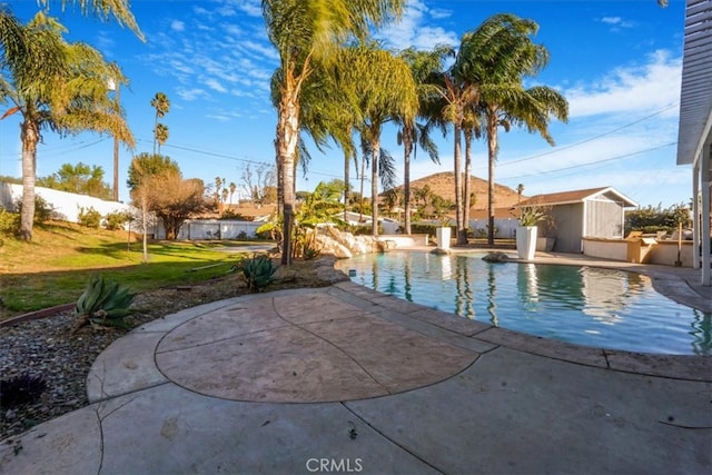 view of pool with a patio area, a yard, and a storage unit