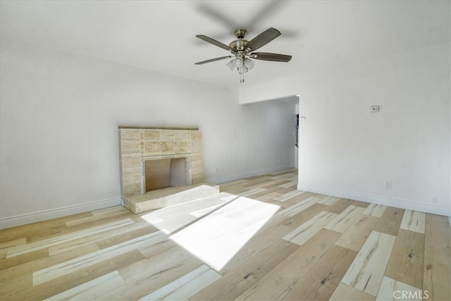 unfurnished living room featuring ceiling fan, light hardwood / wood-style floors, and a stone fireplace