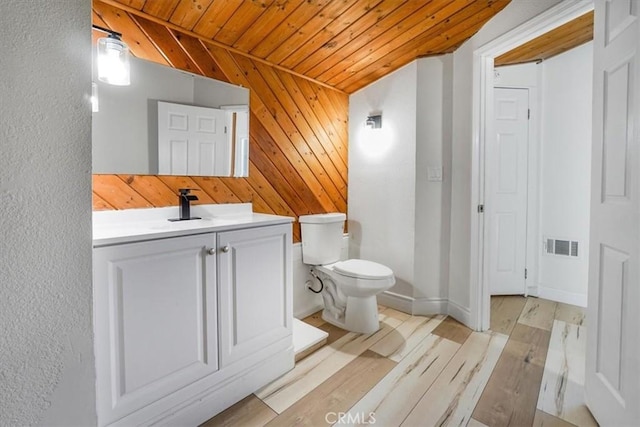 bathroom with toilet, wooden walls, wooden ceiling, wood-type flooring, and vanity