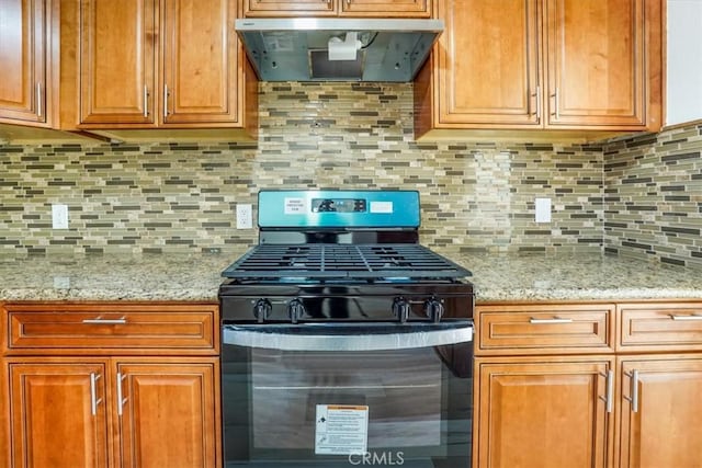 kitchen featuring range hood, decorative backsplash, black gas stove, and light stone countertops