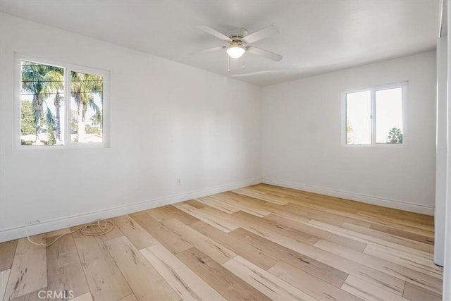 empty room featuring ceiling fan, a healthy amount of sunlight, and light wood-type flooring