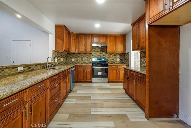 kitchen with decorative backsplash, sink, light hardwood / wood-style flooring, stainless steel appliances, and light stone counters