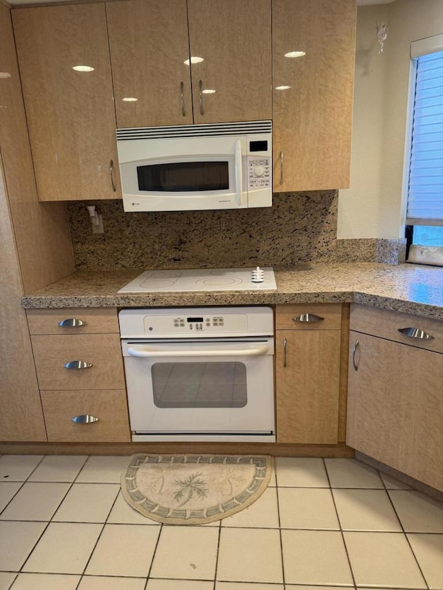 kitchen with tasteful backsplash, light tile patterned floors, and white appliances