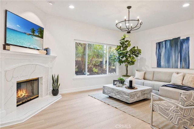 living room with light wood-type flooring, a high end fireplace, and a chandelier