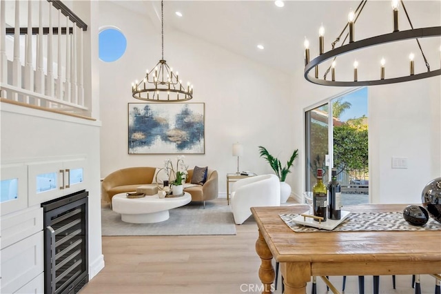 living room featuring a high ceiling, light hardwood / wood-style floors, wine cooler, and an inviting chandelier