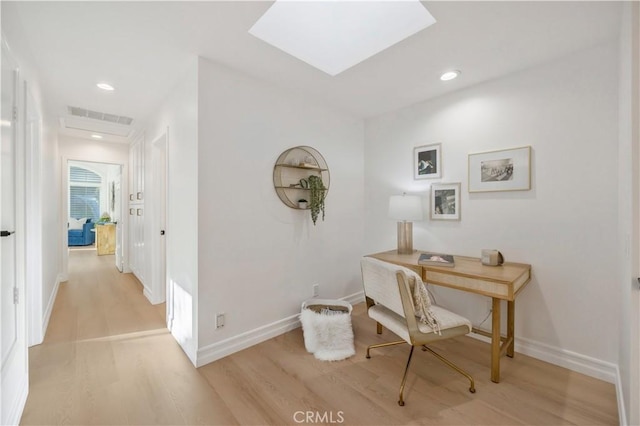 office space with light hardwood / wood-style floors and a skylight