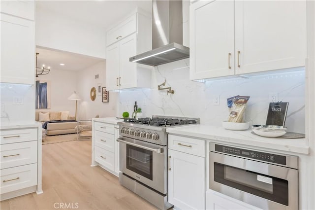 kitchen featuring white cabinetry, oven, light hardwood / wood-style floors, wall chimney exhaust hood, and stainless steel stove