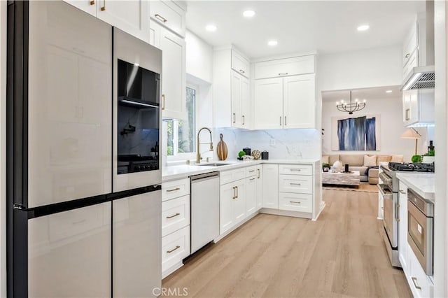 kitchen featuring appliances with stainless steel finishes, light hardwood / wood-style flooring, sink, white cabinetry, and decorative backsplash