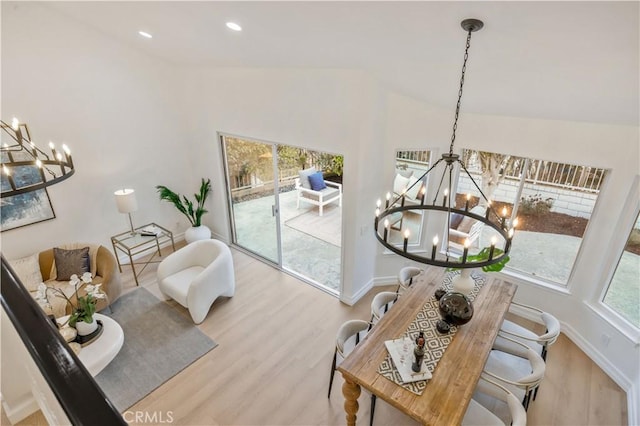 living area featuring light wood-type flooring, lofted ceiling, and a notable chandelier