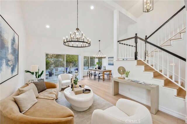 living room featuring a towering ceiling, a chandelier, and light wood-type flooring