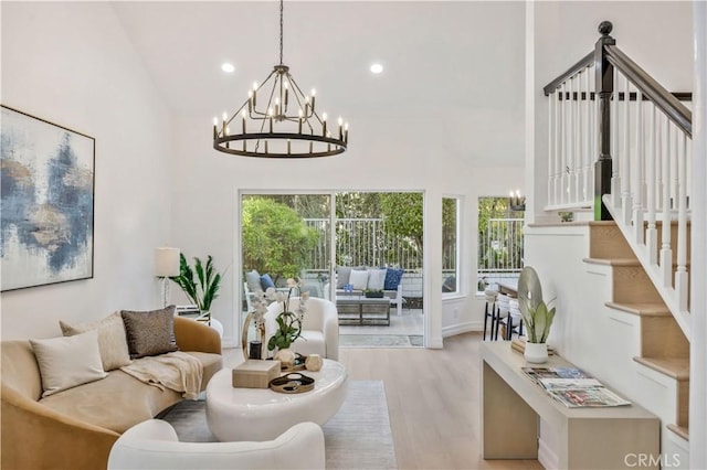 living room featuring plenty of natural light, light wood-type flooring, high vaulted ceiling, and an inviting chandelier