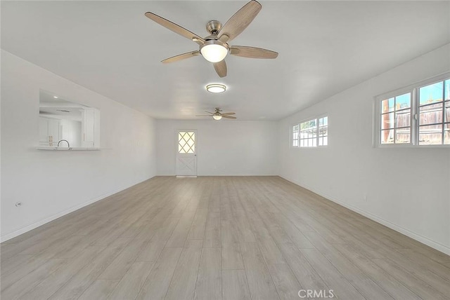 empty room with light hardwood / wood-style floors, sink, and ceiling fan