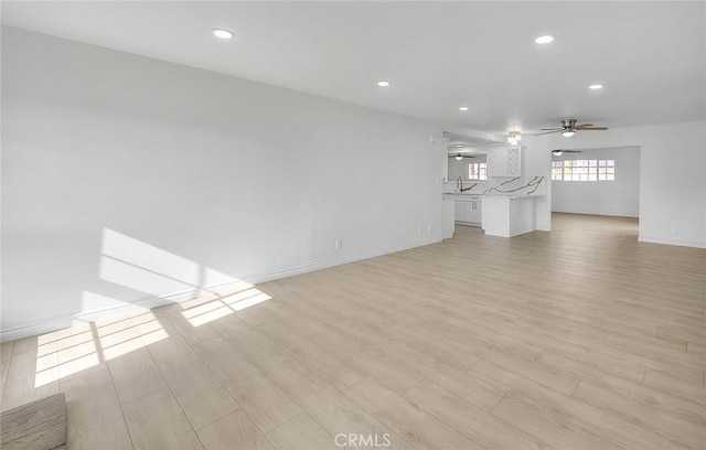 unfurnished living room featuring ceiling fan, light hardwood / wood-style floors, and sink