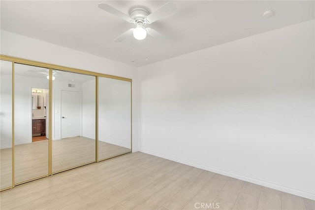 unfurnished bedroom featuring ceiling fan, light hardwood / wood-style floors, and a closet