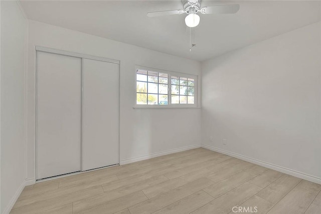 unfurnished bedroom with ceiling fan, light wood-type flooring, and a closet