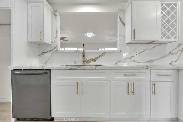 kitchen with light stone countertops, white cabinets, dishwasher, tasteful backsplash, and sink