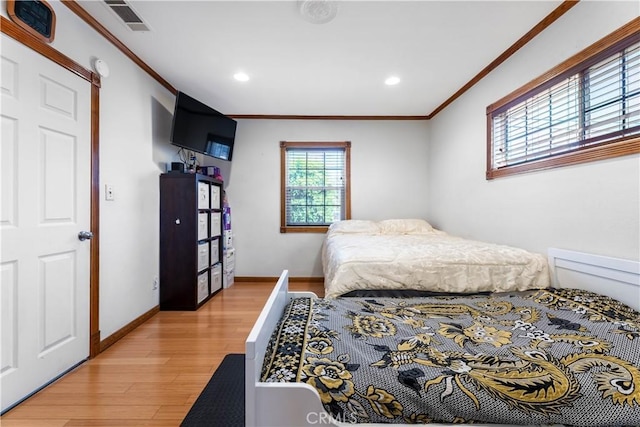 bedroom featuring crown molding and light hardwood / wood-style flooring