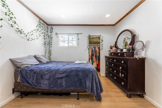 bedroom featuring light hardwood / wood-style floors, a closet, a spacious closet, and crown molding