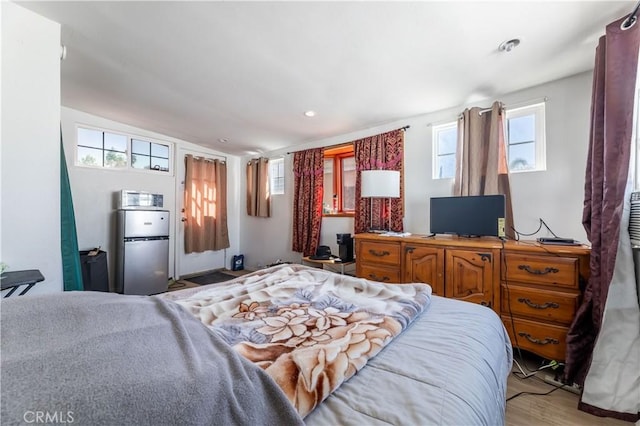 bedroom with wood-type flooring and stainless steel fridge