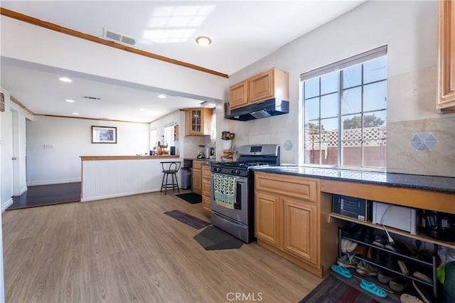 kitchen featuring light brown cabinets, tasteful backsplash, stainless steel gas stove, ornamental molding, and light wood-type flooring