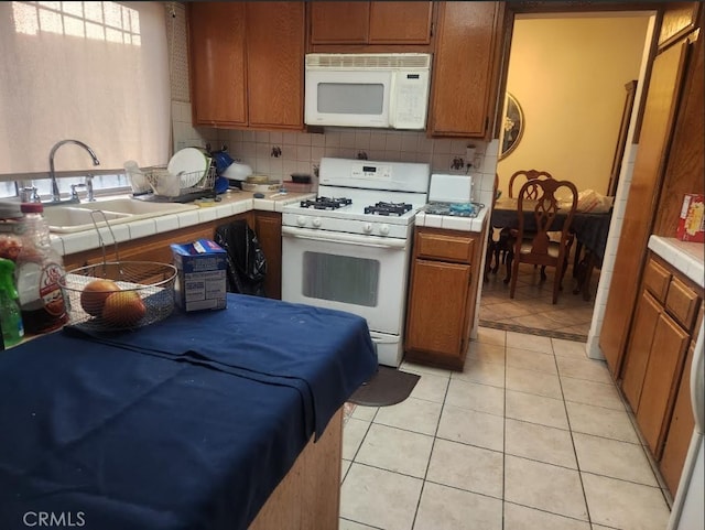 kitchen with sink, tasteful backsplash, light tile patterned floors, tile counters, and white appliances