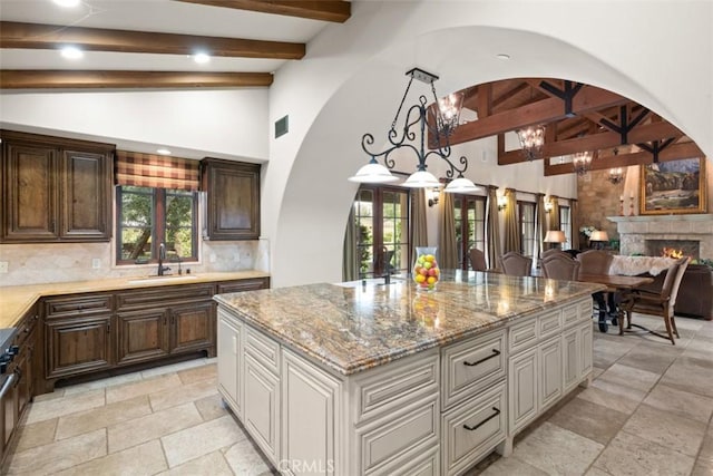 kitchen with a kitchen island, decorative backsplash, sink, french doors, and a chandelier