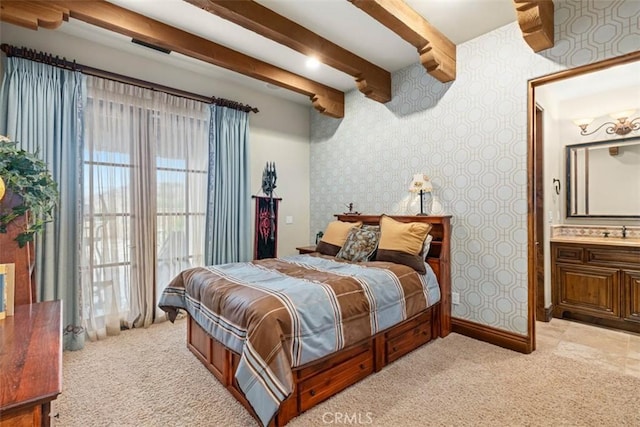 bedroom featuring ensuite bathroom, light colored carpet, and beamed ceiling