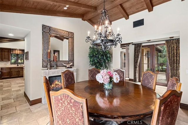 dining area with vaulted ceiling with beams, french doors, a chandelier, and wooden ceiling