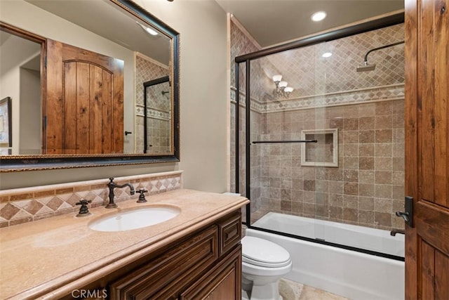 full bathroom with toilet, backsplash, vanity, and shower / bath combination with glass door