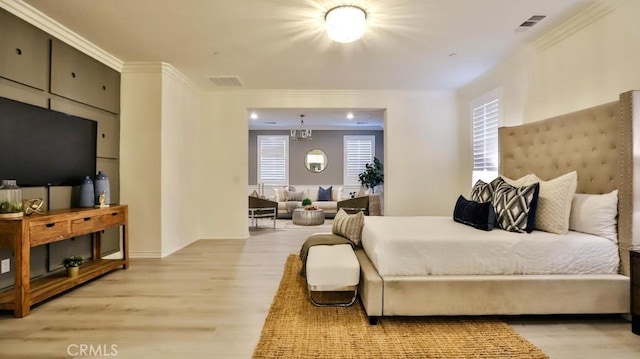 bedroom featuring light hardwood / wood-style flooring, ornamental molding, and a chandelier