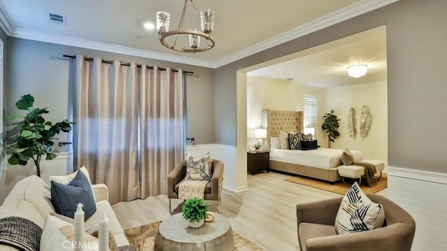 bedroom featuring an inviting chandelier, ornamental molding, and light hardwood / wood-style floors