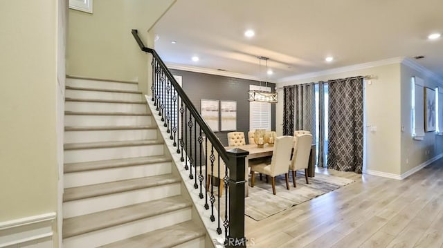 stairway with an inviting chandelier, ornamental molding, and hardwood / wood-style floors