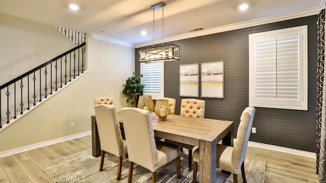 dining area featuring brick wall, crown molding, and light hardwood / wood-style flooring