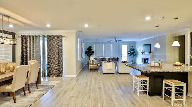 kitchen with ornamental molding, pendant lighting, light hardwood / wood-style flooring, and light stone countertops