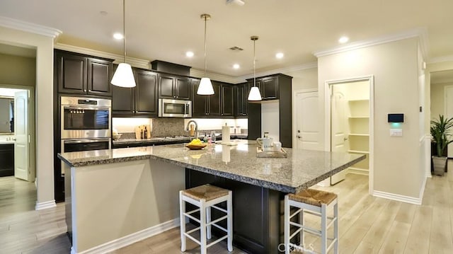 kitchen featuring a breakfast bar, stainless steel appliances, a large island, and decorative light fixtures