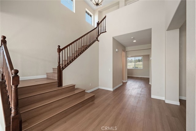 staircase with a high ceiling, hardwood / wood-style floors, and a notable chandelier