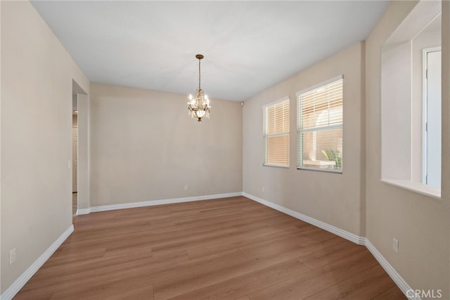 spare room featuring an inviting chandelier and light wood-type flooring