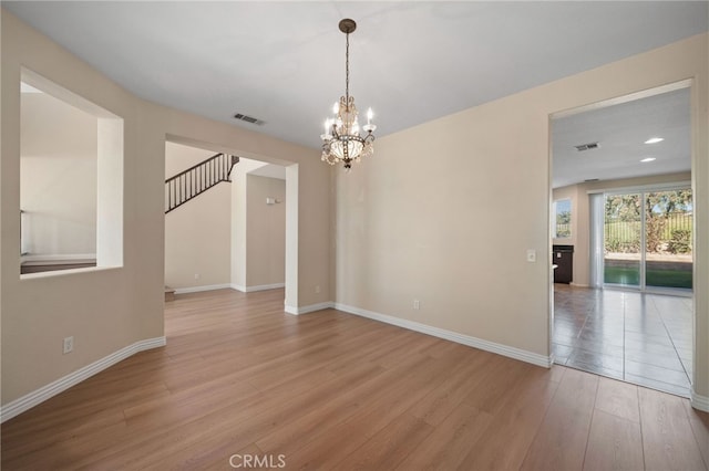 spare room featuring an inviting chandelier and light wood-type flooring