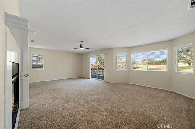 unfurnished living room with light carpet, ceiling fan, and a textured ceiling