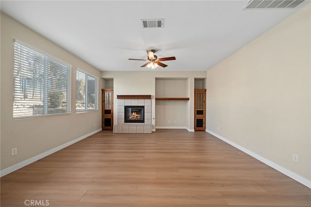 unfurnished living room with a fireplace, ceiling fan, and light hardwood / wood-style flooring