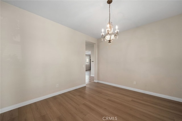 unfurnished room with wood-type flooring and an inviting chandelier