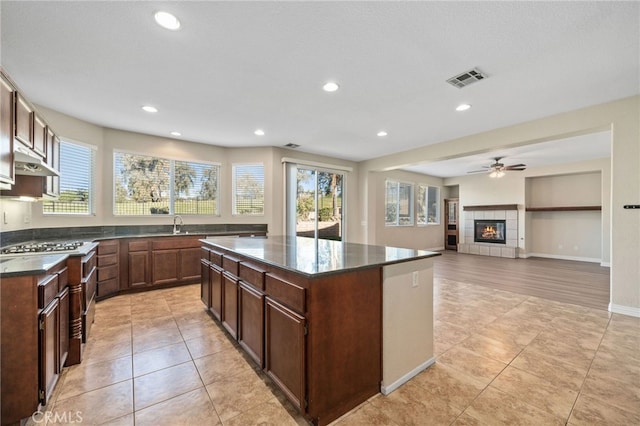 kitchen with a center island, sink, a tile fireplace, and light tile patterned floors