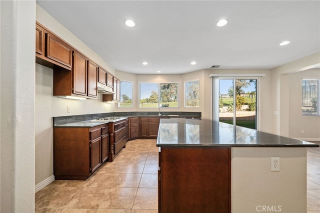 kitchen with a center island, light tile patterned floors, and dark stone counters