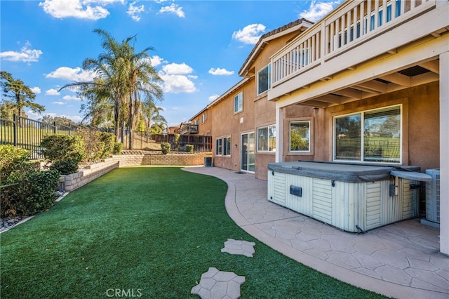 view of yard featuring a hot tub, a balcony, and a patio area