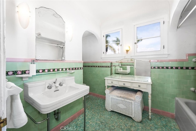 bathroom with tile walls, sink, and a bathtub