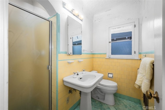 bathroom featuring tile walls, a shower with door, and toilet