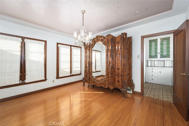 unfurnished room featuring an inviting chandelier and light hardwood / wood-style flooring