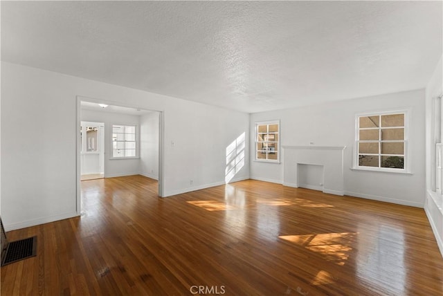 unfurnished living room with wood-type flooring and a textured ceiling